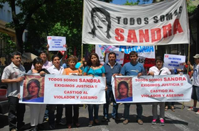 Fotografía de la cabecera de la movilización en el marco del juicio por el femicidio de Sandra Ayala Gamboa. En la imagen puede verse la bandera "Todas somos Sandra" y otras de organizaciones sociales y políticas de la época.